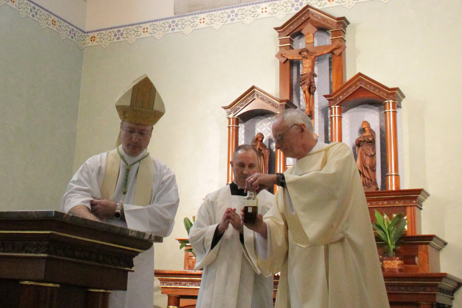 Bishop W. Shawn McKnight consecrates the new altar in St. Stanislaus Church in Wardsville with the Oil of Sacred Chrism. Assisting him is Deacon Alan Sims of the Wardsville parish and Father Louis Nelen, pastor of Cathedral of St. Joseph parish in Jefferson City, serving as master of ceremonies.
